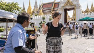 Traveler checking directions before accepting a tuk-tuk ride near a Bangkok temple